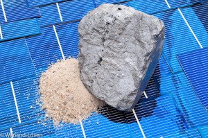 Bergje zand en blokje silicium op een ondergrond van zonnecellen