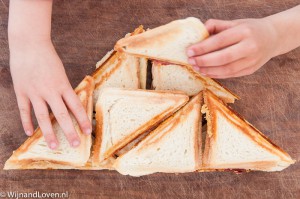 Foto van Een stapel heerlijke tosti's met kinderhanden.