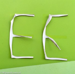 Foto in de categorie cijfers en letters: twee stickers van de letter E die los hebben gelaten van de groene ondergrond. 