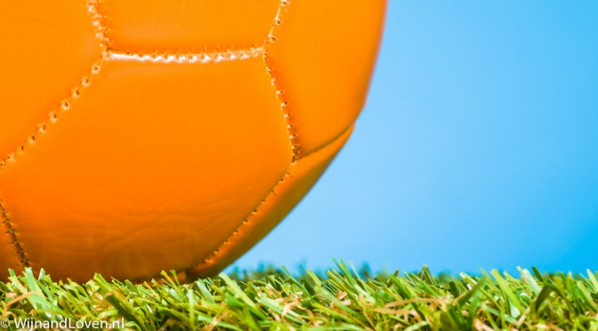 oranje voetbal op gras tegen een blauwe lucht
